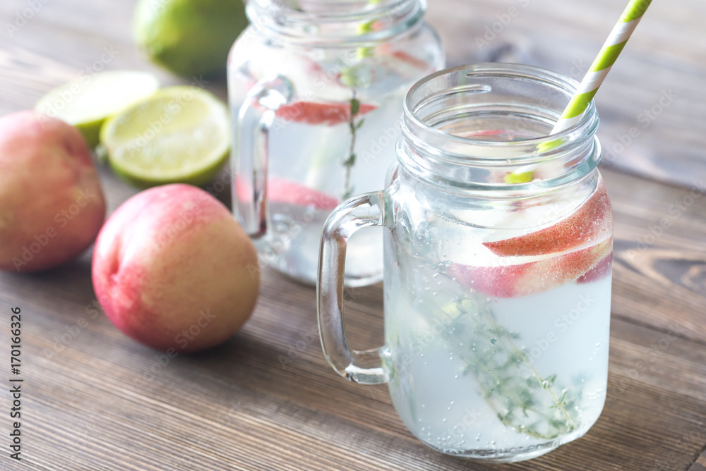 Glass jar of lime water with slices of peach Glass jar of lime water with slices of peach