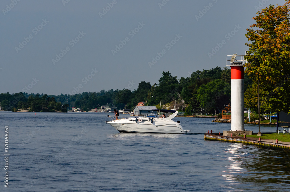 Powerboat entering St. Lawrence River beside a lighthouse