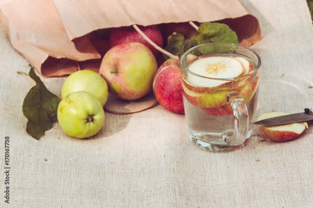 a glass of autumn apple drink on a rustic textile background, fresh apples a glass of autumn apple drink on a rustic textile background, fresh apples