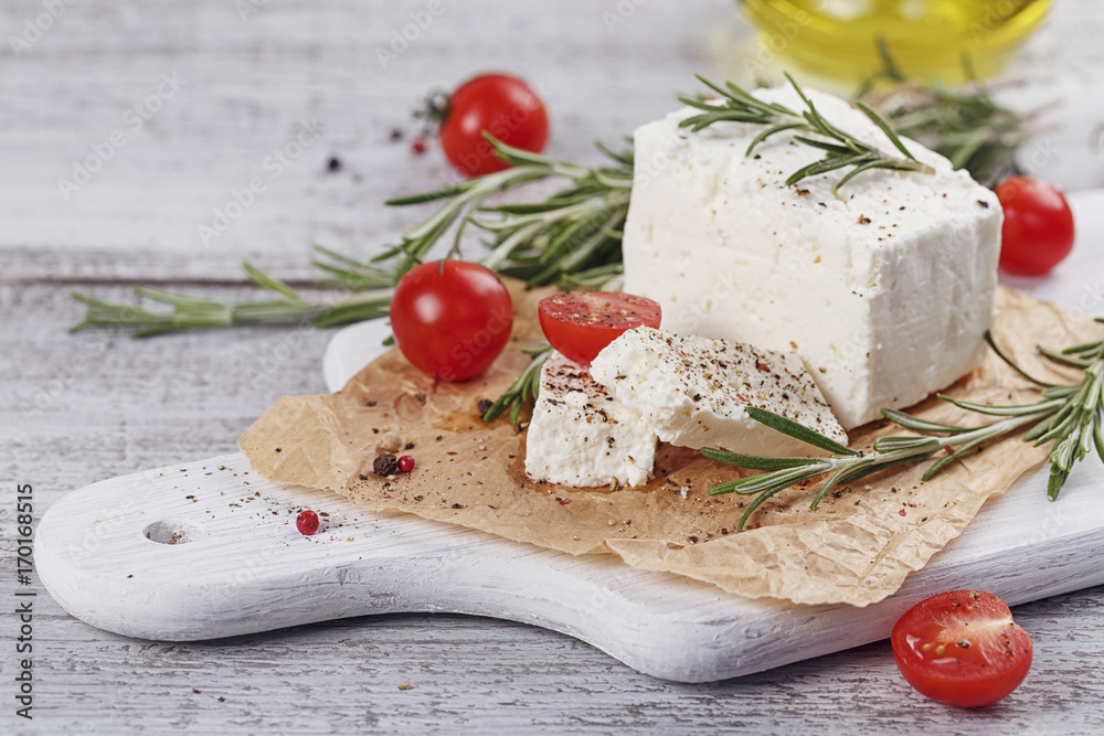 Fresh feta cheese with rosemary on white wooden serving board Fresh feta cheese with rosemary on white wooden serving board
