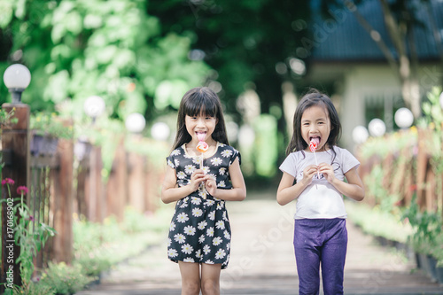 Two little girls relaxing play in the park and eat lollipops © luvvstudio