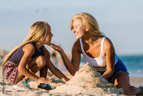 Mother and daughter making sand castle at tropical beach