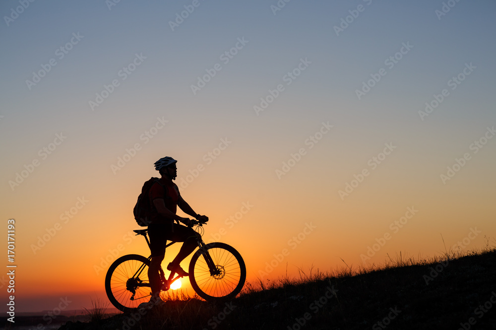 Silhouette man stand with mountain bike on the meadow