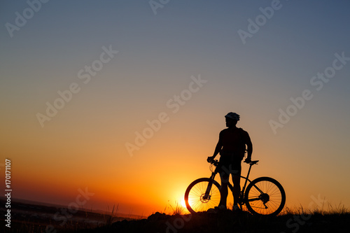 Silhouette man stand with mountain bike on the meadow