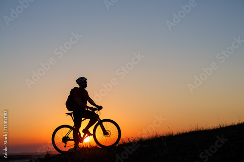Silhouette man stand with mountain bike on the meadow © Aleksey