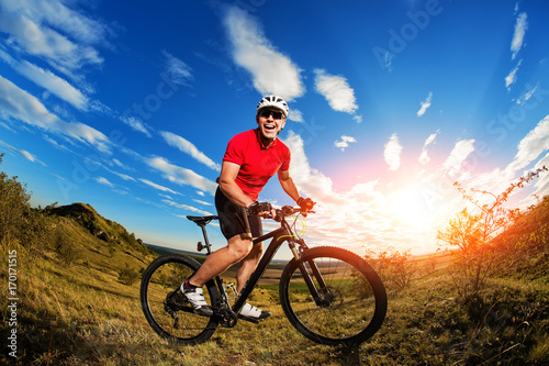 low angle view of cyclist standing with mountain bike on trail at sunset