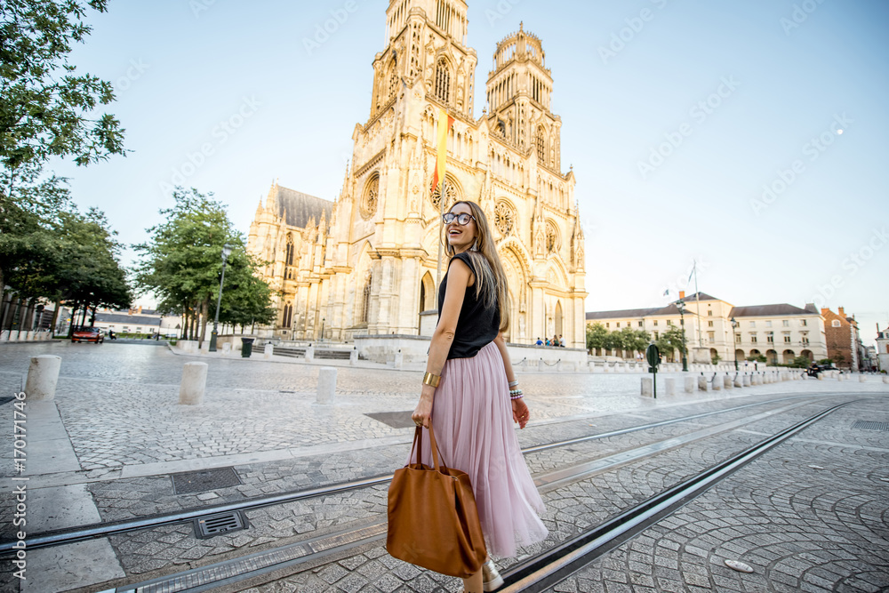 Lifestyle portrait of a woman walking near the famous cathedral during the sunset in Orleans, France