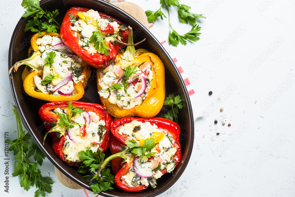 Stuffed paprika peppers with cheese and herbs. Top view on white. Stuffed paprika peppers with cheese and herbs. Top view on white.