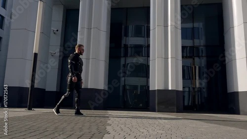 Wallpaper Mural slow motion. a bearded man in black leather clothes runs along modern office building at the tile the road Torontodigital.ca