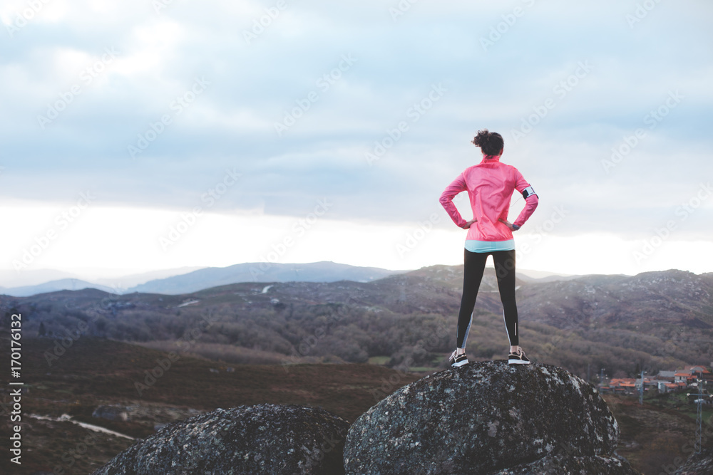 Obraz premium Athletic woman examines the landscape for training in the mountains. Sport tight clothes. 