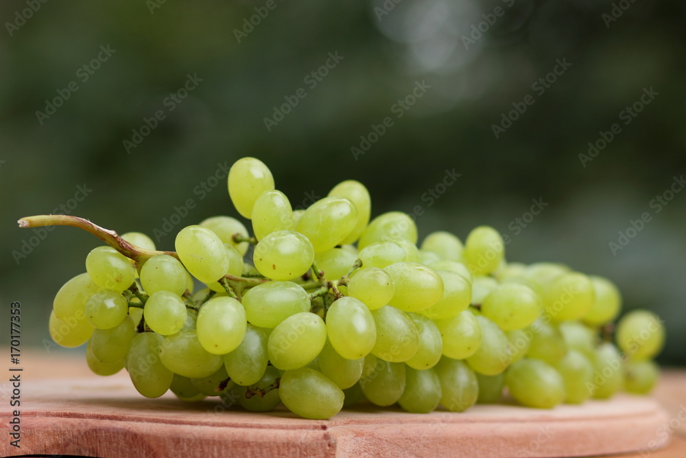 A bunch of green grapes in a wooden basket on a window A bunch of green grapes in a wooden basket on a window