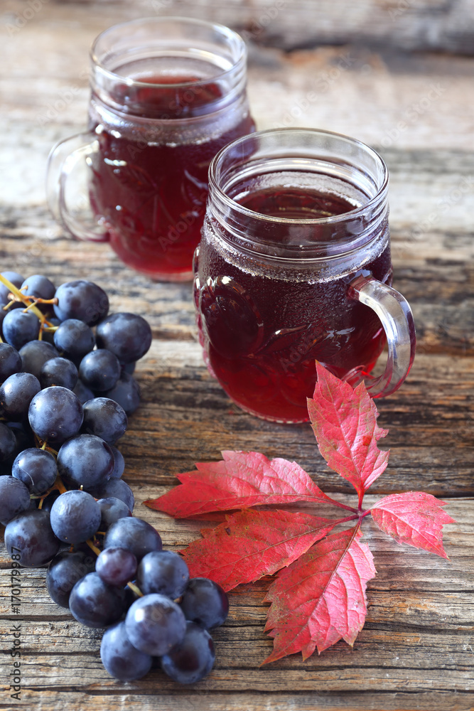 Glasses of grape juice, black grapes and autumn leaves Glasses of grape juice, black grapes and autumn leaves