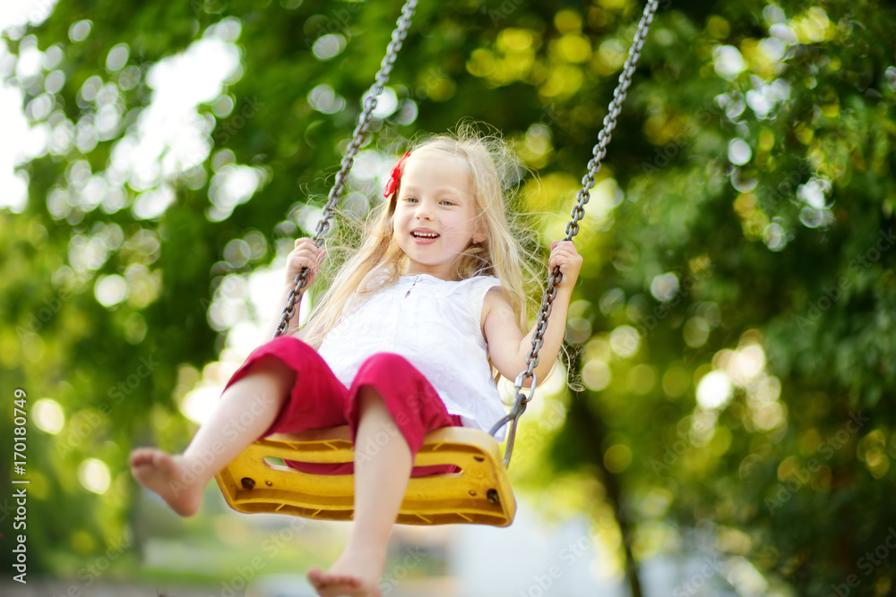Cute little girl having fun on a playground outdoors on warm summer day Cute little girl having fun on a playground outdoors on warm summer day