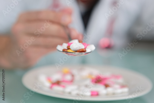 hand holding a spoon full of pills