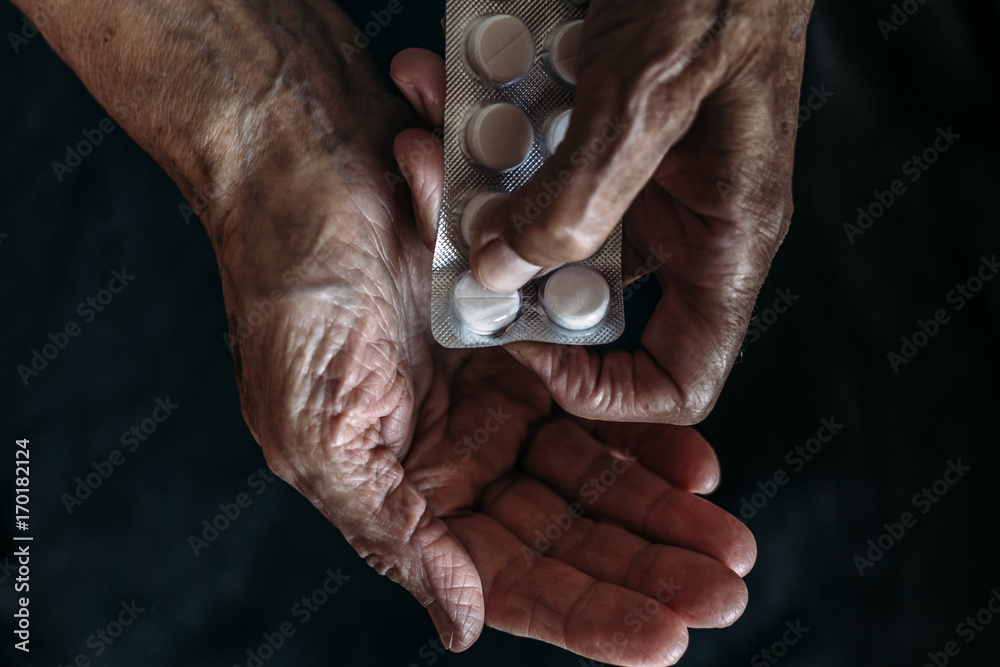 Hands of old woman with tablets or pills.  Health care and Taking medication of old people