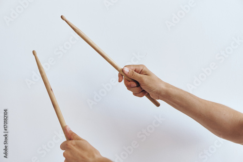 The hands hold the drumsticks