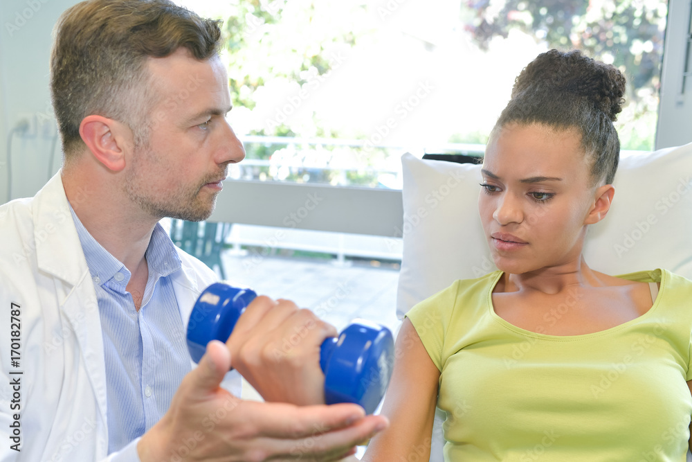 Obraz premium physiotherapy doing arm exercises with dumbbells