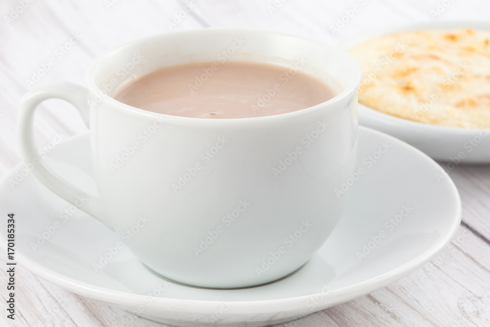 Cup of hot chocolate with cheese and arepa served in white dishware