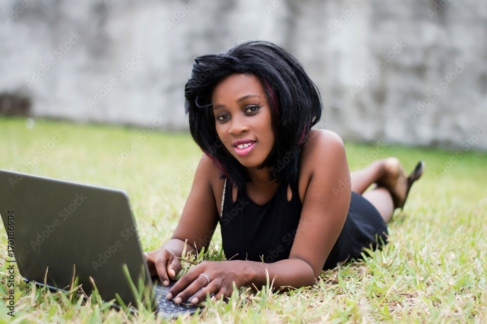 Beautiful business woman laying on grass and using laptop Beautiful business woman laying on grass and using laptop
