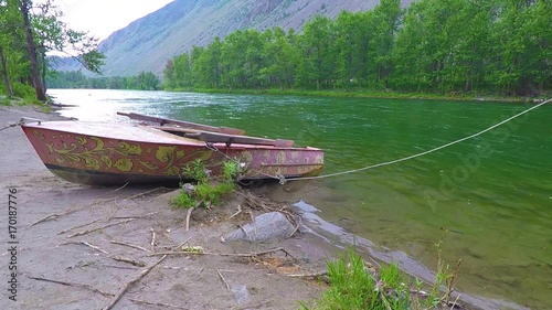 Boats on the shore of the taiga river in the foothills of the mountains photo