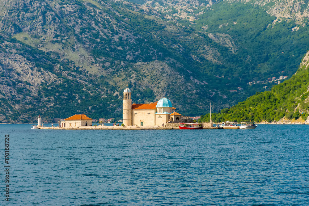 The yacht sails near the picturesque Gospa od Skrpela Island in the Boka Kotorsky Bay.