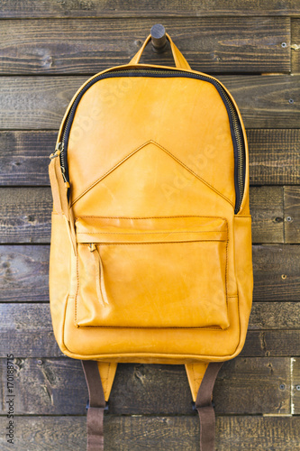Yellow leather backpack for traveler on the wooden background