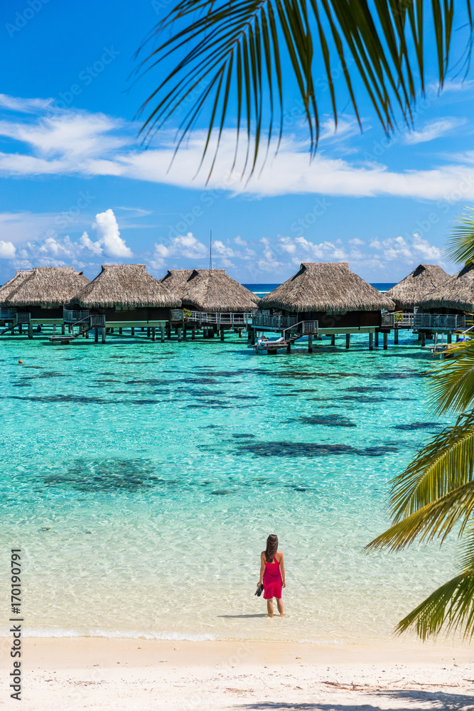 Luxury beach travel vacation woman in Tahiti. Tourist enjoying ocean water at overwater bungalow hotel villas in French Polynesia, Moorea island in south pacific, famous getaway destination. - obrazy, fototapety, plakaty 
