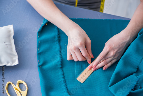 Woman tailor working on a clothing sewing stitching measuring fa