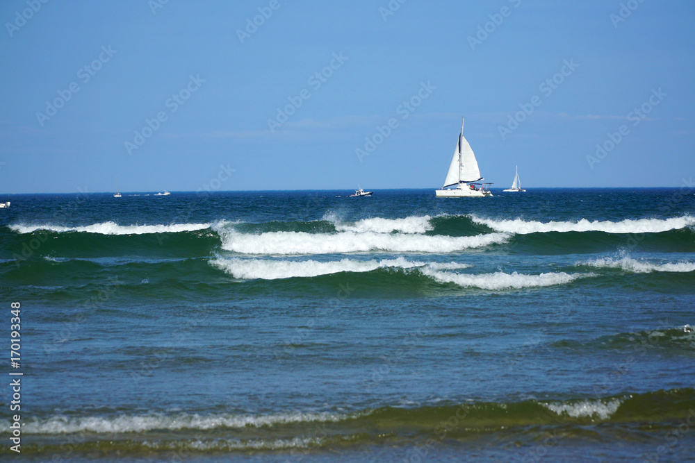 tidal waves in the sea with remote sailboat