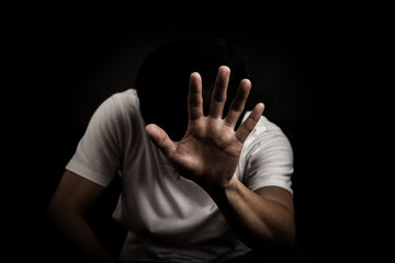 Man show hand stop sign and sit felling sad worry dark tone on black background