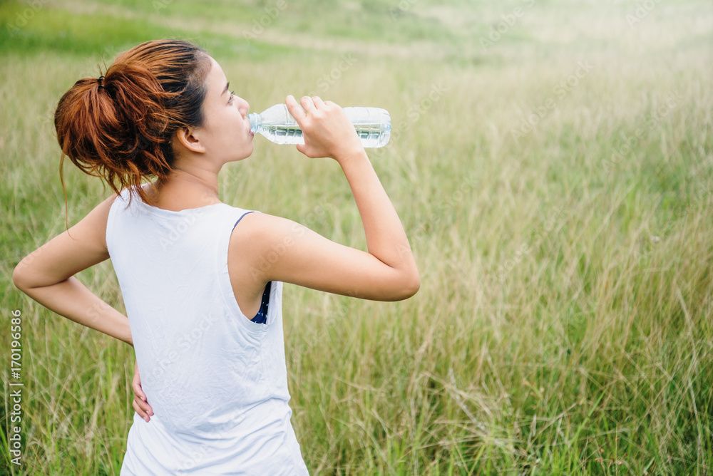 Asian women relax in the holiday. Drink Water on a green pasture. Asian women relax in the holiday. Drink Water on a green pasture.