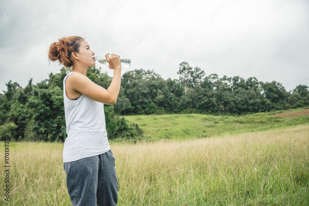Asian women relax in the holiday. Drink Water on a green pasture. Asian women relax in the holiday. Drink Water on a green pasture.