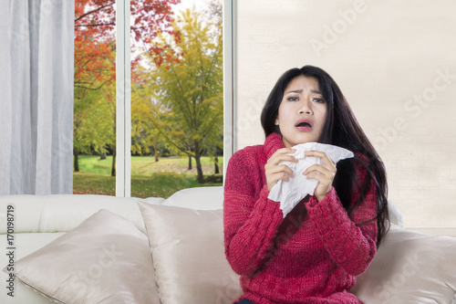 Sick woman sneezing on sofa