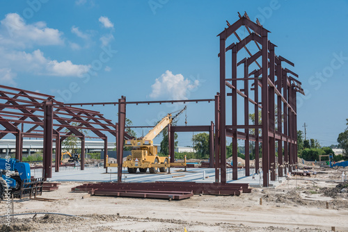 Steel structure of new industrial building under cloud blue sky. New technology structural frame beam of factory in construction. Steel frame manufacturer and crane, telescopic forklift, sand, gravel photo