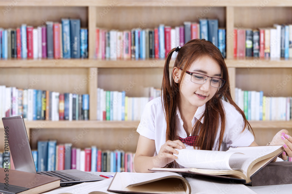 Pretty teenage student learns in library Pretty teenage student learns in library