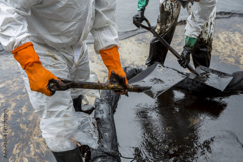 Fotografi Workers remove crude oil from a beach, Crude oil on oil spill