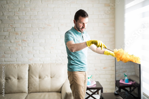 Photography Handsome Latin man dusting his house