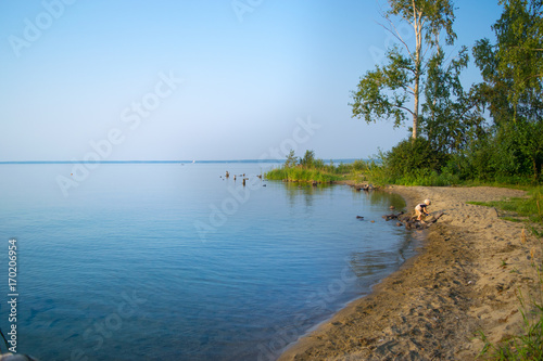 Fototapeta Naklejka Na Ścianę i Meble -  Shore of Lake with baby playing with sand, Uveldy (Увельды), the Urals