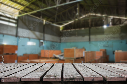 Wooden floor or wooden table with blurred image of warehouse for background.