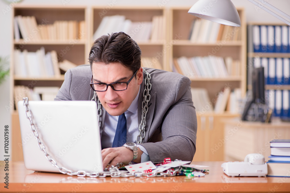 Obraz premium Young businessman addicted to online gambling cards playing in t