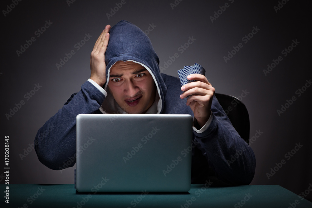 Young man wearing a hoodie sitting in front of a laptop computer Young man wearing a hoodie sitting in front of a laptop computer