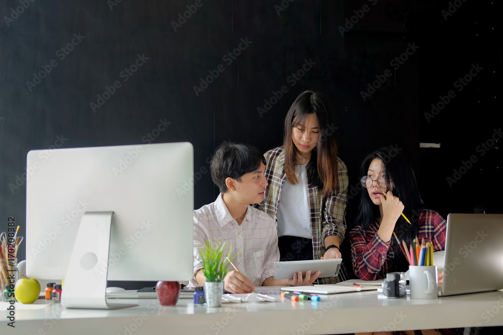 Fototapeta premium Designers Brainstorming concept : Young creative designer team working with new startup project in modern office. Contemporary notebook on wood table.
