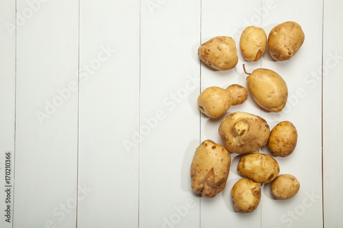 Raw potatoes on a white wooden background