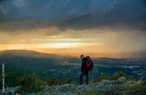 Amazing sunset on a mountain top - man with alpine equipment enjoying the breathtaking view under the stormy sky © photoenthusiast