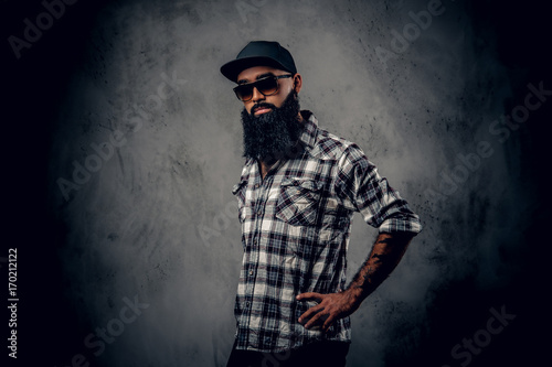 Black bearded male posing over grey background.