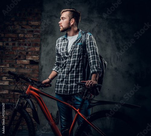 A mant holds red mountain bicycle. photo