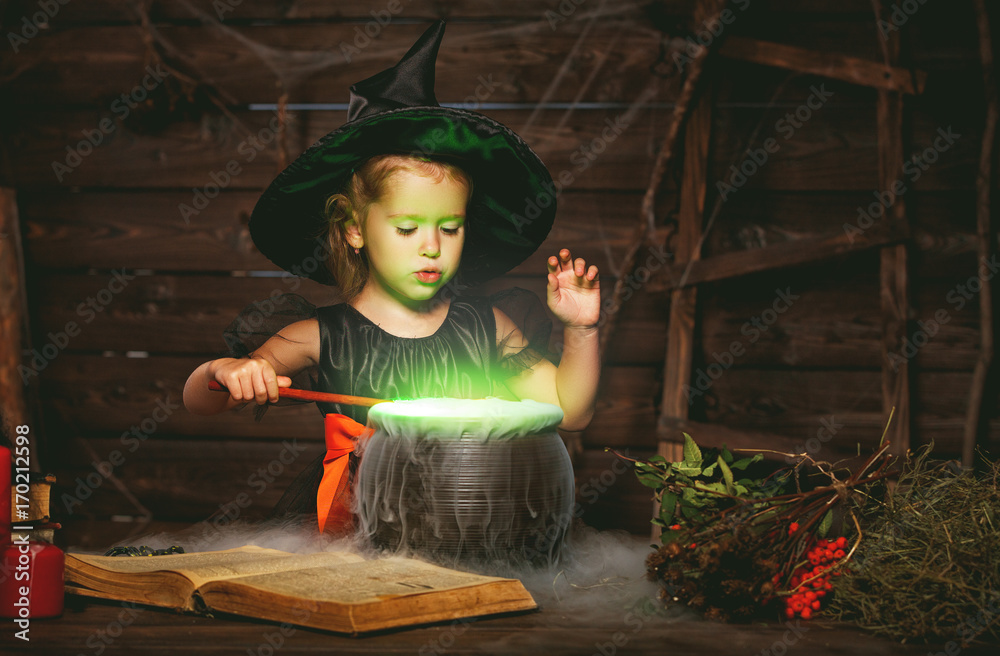 Fototapeta premium Halloween. little witch child cooking potion in cauldron with spell book