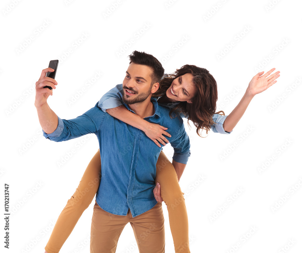 woman on the back of man while he takes selfie woman on the back of man while he takes selfie