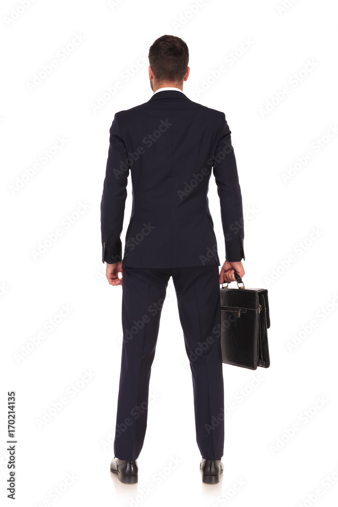 back view of a standing business man holding briefcase back view of a standing business man holding briefcase