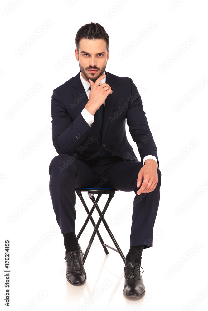 young pensive business man is sitting on a chair young pensive business man is sitting on a chair